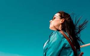 Девушка с развивающимися волосами на фоне ярко голубого неба